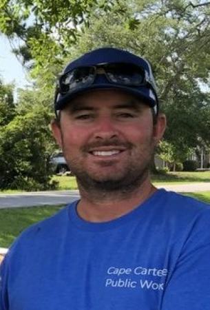 Ryan Hutchinson wearing a blue shirt and baseball cap smiling at the camera